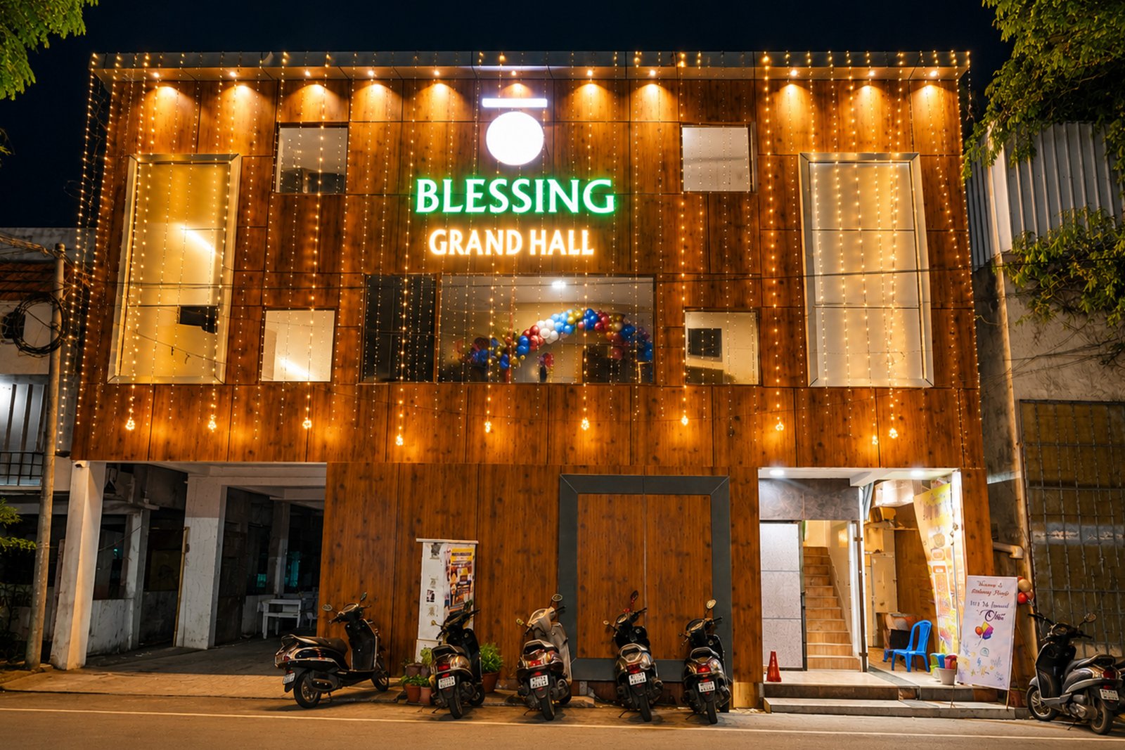 The building lit up at night with fairy lights on the wooden façade